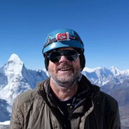 A portrait of guide Eric Schulz on a mountain peak